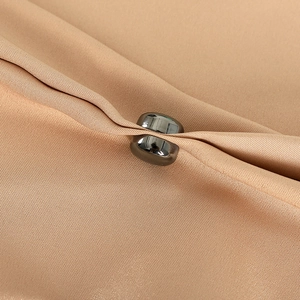 Close-up of silver magnetic hijab clip holding beige silk fabric with elegant metal finish