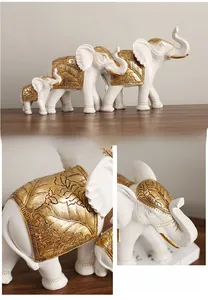 Detail of three resin elephant statues with intricate golden leaf relief patterns