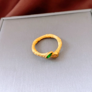 Macro shot of gold bamboo textured ring featuring a marquise green gemstone and zircon accents