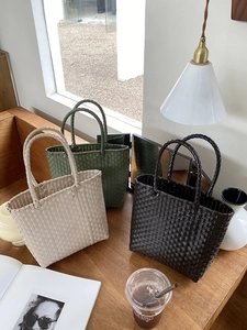 Three variants of woven tote bags in beige, dark green, and brown on a wooden desk