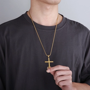 Close-up of a gold cross pendant necklace featuring a creative wheat pattern on a male model