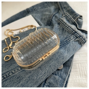 Macro shot of a transparent striped acrylic box bag with gold chain on denim