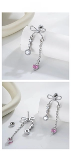 Detail view of silver bow earrings with chain fringe and pink heart-shaped crystal
