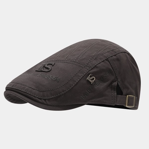 Detail of vintage charcoal canvas flat cap showing metal S logo and premium embroidery