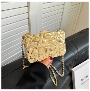 Macro shot of gold evening clutch bag with hammer texture and metallic chain strap