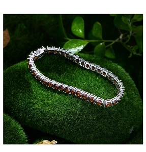 Makroaufnahme von Silber-Tennisarmband mit bernsteinfarbenen Steinen auf Moos