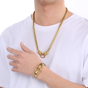 Close-up of golden punk skull lobster clasps on thick Cuban link chain jewelry set