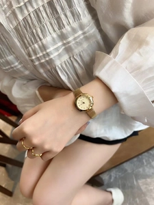 Close-up of elegant gold octagonal watch with thin chain strap on woman wrist