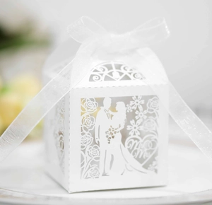 Detail of white laser-cut wedding favor box with Mr & Mrs silhouette and organza ribbon