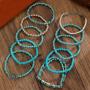 Detailed view of turquoise beads and silver metal bracelets on dark wood background