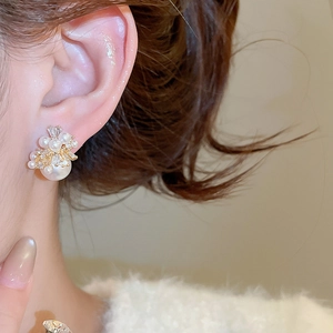 Close-up of model wearing pearl and rhinestone stud earrings with gold metal base