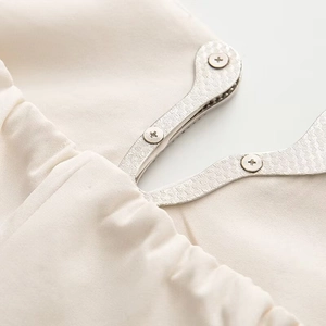 Macro detail of beige fabric texture and silver metallic rhinestone fastener on dress