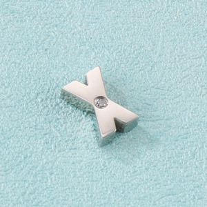 Macro shot of silver metal letter X pendant featuring a sparkling clear gemstone inlay