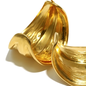 Macro detail of 18K gold plated stainless steel C-shape earring with wavy texture