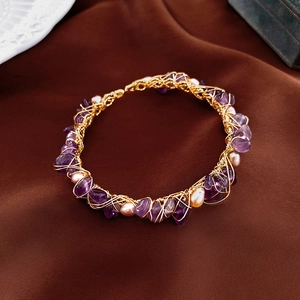 Detail of hand-woven gold-plated wire bracelet with purple stones and freshwater pearls