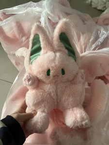 Close-up of a pink plush rabbit with bat wings featuring green ears and soft fur texture
