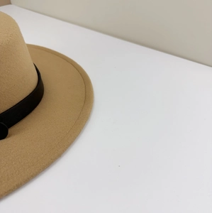 Detail of khaki wool fedora hat featuring a stylish black belt buckle decoration