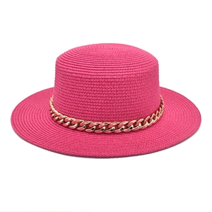 Détail d'un chapeau de paille rose fuchsia orné d'une grosse chaîne en acrylique doré