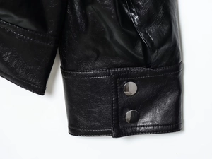 Detailed macro view of black faux leather jacket cuffs with silver metallic snap buttons