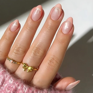 Macro detail of pink glitter press-on nails with bow and star patterns for a sweet style