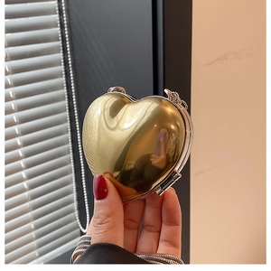 Close-up of a glossy gold heart-shaped mini acrylic bag with a sleek metallic snake chain