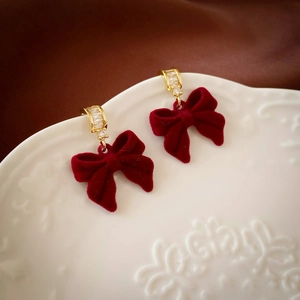 Détail de boucles d'oreilles nœud rouge avec texture velours et zircon sur assiette