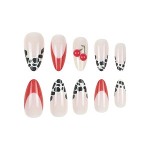 Almond press-on nails with red French tips, cow print patterns, and 3D cherry accents