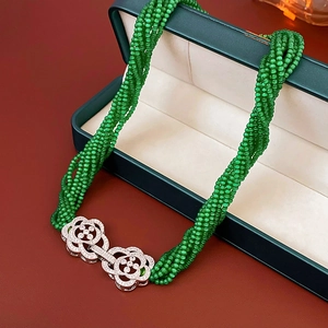 Close-up of multilayered green bead necklace with a zircon-set flower clasp detail