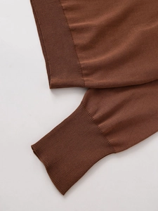 Detailed close-up showing the ribbed cuffs and fine knit texture of the brown sweater