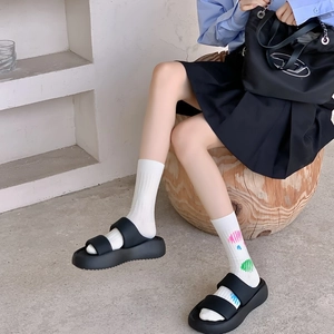 Close-up of black platform sandals paired with white patterned combed cotton socks