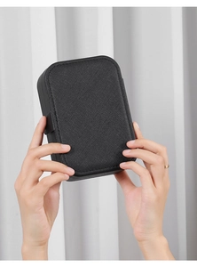 Close-up of a compact black PU leather jewelry box held by a hand for size comparison