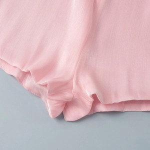 Detailed view of pink chiffon dress ruffle hem with fine silk texture and neat stitching