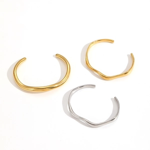 Close-up of irregular wave bangle in 18k gold and silver finish on white backdrop