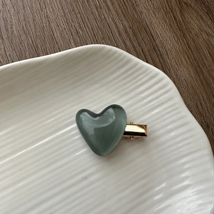 Close-up of a jelly blue heart hair clip on a white plate over a dark wooden background
