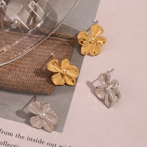 Close-up of matte brushed metal flower earrings in gold and silver finishes