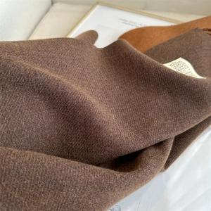 Detailed close-up of dark brown cashmere scarf fabric texture with woven brand label
