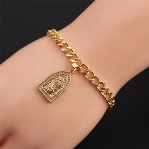 Macro view of gold plated Cuban chain bracelet with Virgin Mary pendant on woman's wrist