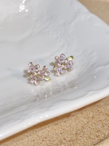 Close-up of lilac flower earrings with shimmer texture on a white ceramic plate