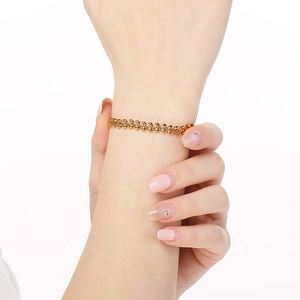 Golden wheat chain bracelet in stainless steel shown on a wrist with white background
