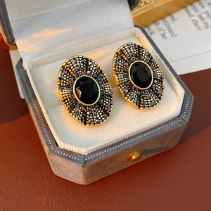 Dettaglio macro degli orecchini vintage dorati con gemma nera e piccoli strass