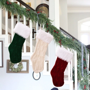 Three knitted Christmas stockings in green, beige, and red hanging on stairs with pine