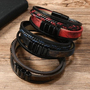Set of stacked multi-layer braided leather bracelets in red, blue, and brown on wood surface