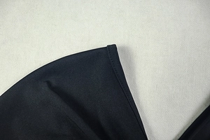 Detailed close-up of double-needle stitching on black elastic knit fabric for quality finish