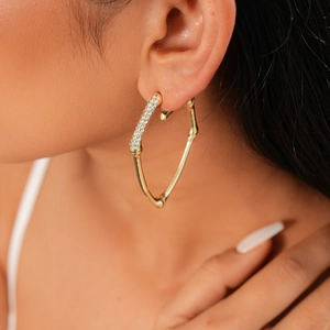 Close-up of a gold heart hoop earring with rhinestones on a model's ear