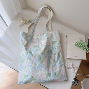 Detail of floral cotton tote bag with white woven label on a minimalist desk