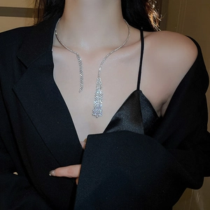 Detail view of a silver tassel necklace with zircons worn by a model in a black suit