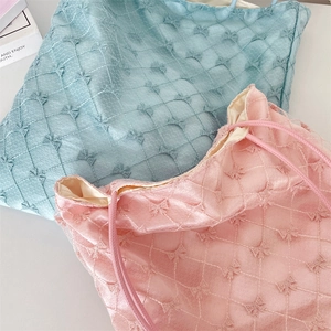 Detailed close-up of quilted bow patterns on light blue and pink tote bags texture