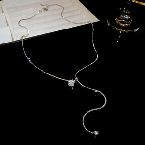 Detail of silver snake chain necklace with Y-shaped tassel and sparkling round zircon pendant