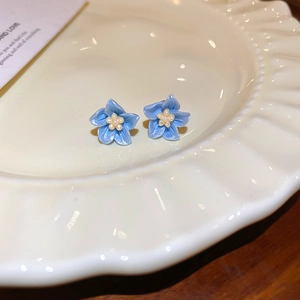 Vue détaillée des boucles d'oreilles fleurs bleu clair avec perle jaune sur plateau