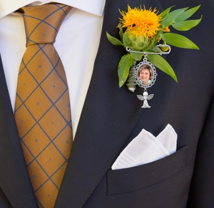 Detail of silver vintage photo charm brooch with angel pendant on wedding suit lapel